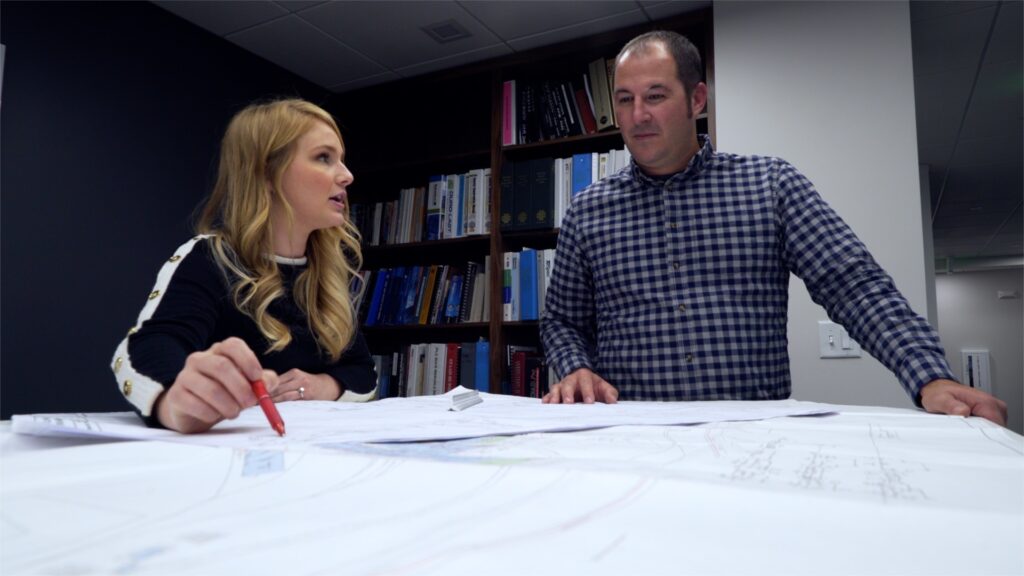photo of man and woman engineers working at a table over schematics