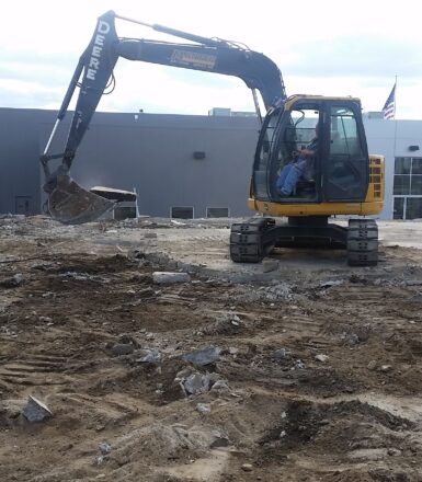 photo of excavation equipment at a construction site digging up a parking lot