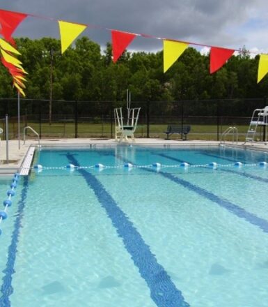 photo of a municipal swimming pool with diving board and lifeguard chair