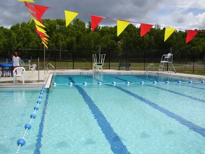 photo of a municipal swimming pool with diving board and lifeguard chair