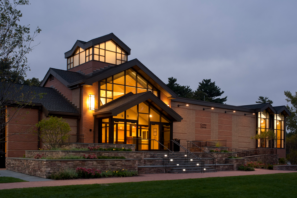 Image of the Rivers Campus Center taken at dusk with the amber glow of the windows lighting up the building from the inside.